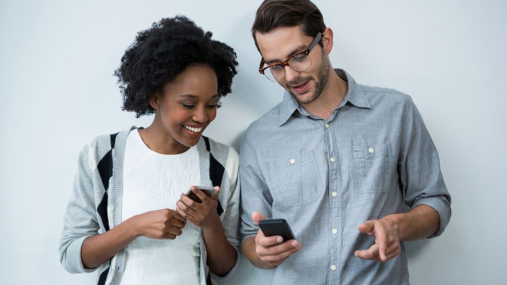 Um homem e uma mulher, cada um segurando o seu celular, compartilham o Wi-Fi pelo QR Code.