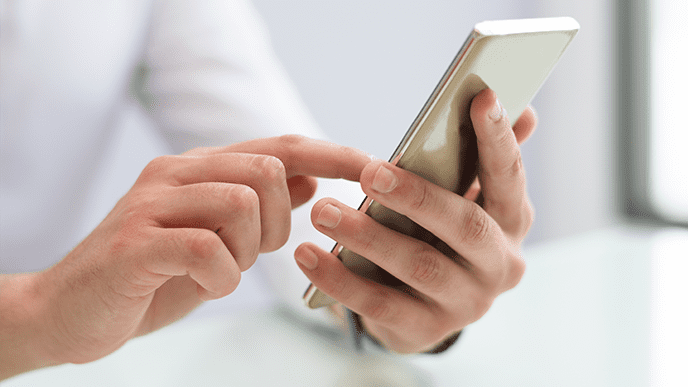 Uma pessoa segurando o celular. Enquanto a mão esquerda segura o aparelho, com o dedo indicador direito a pessoa digita no celular.