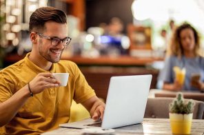 Um homem tomando café e usando o notebook conectado à internet da Desktop com Wi-FI 6.