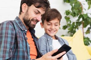 Pai e filho lendo no celular. Eles usam o aplicativo do Skeelo.