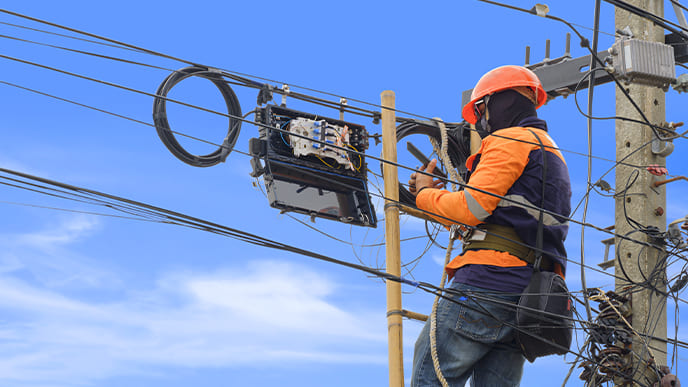 Um técnico de internet instalando a rede de fibra óptica em um poste de energia.
