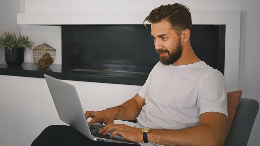 Um homem usando o notebook e conectado ao plano de 400 Mega da Desktop