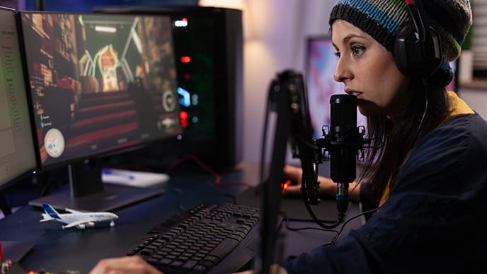 Mulher com roupa de frio e touca, jogando no computador conectado à internet da Desktop.