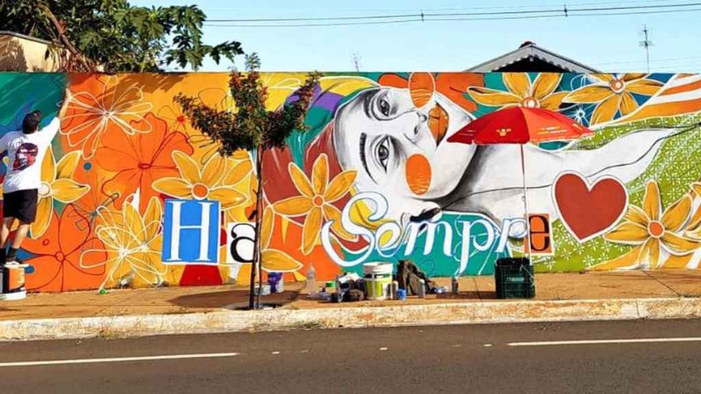 Muro sendo pintado graças a parceria da Desktop com artistas das cidades onde o provedor de internet atua. Na imagem, a representação de uma mulher, flores, um coração e o texto "Sempre".