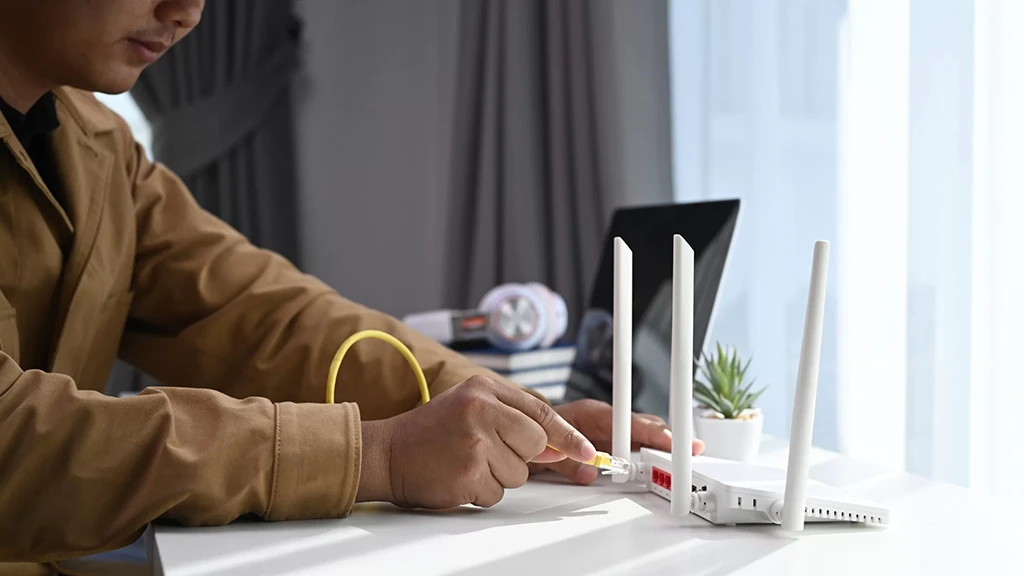 Um homem conectando o cabo de internet no roteador