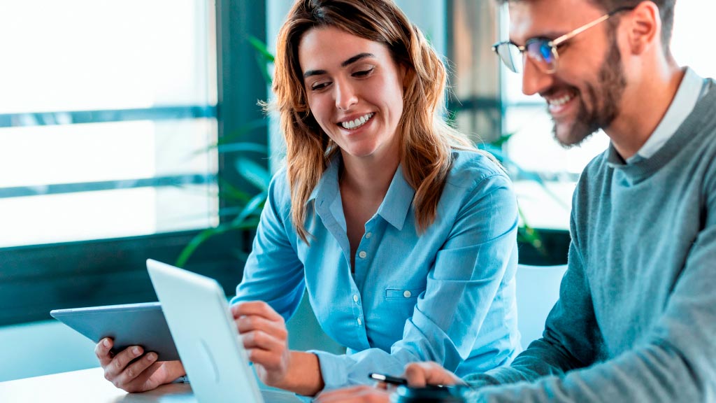 Na imagem, um homem e uma mulher trabalhando juntos em um notebook.