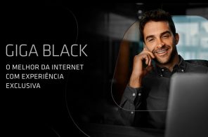 Na imagem, um homem vestindo uma camisa social preta fala ao telefone. Na frente dela a tela de um notebook. Em um fundo texto, o texto 