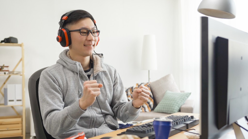 Rapaz gamer de PC, usando óculos, fones de ouvido e moletom cinza, comemorando ao descobrir se um jogo roda em seu computador