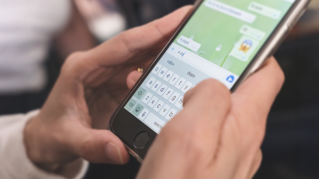 Mãos de um homem segurando celular com conversa aberta representando como formatar texto no WhatsApp
