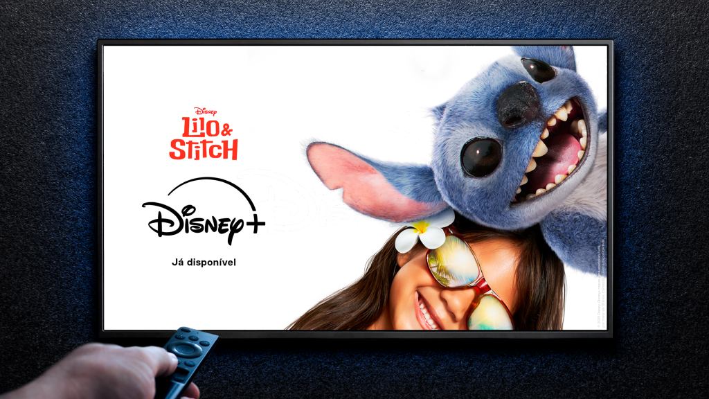 Pessoa com o controle de remoto na mão apontado para a TV, que exibe a imagem do Lilo & Stitch, disponível no Disney+.