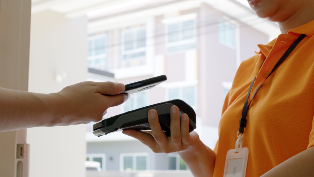 Pessoa realizando pagamento com NFC no celular na maquininha para atendente vestindo uniforme laranja.