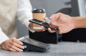 Pessoa realizando pagamento com NFC no celular aproximando o aparelho à maquininha.