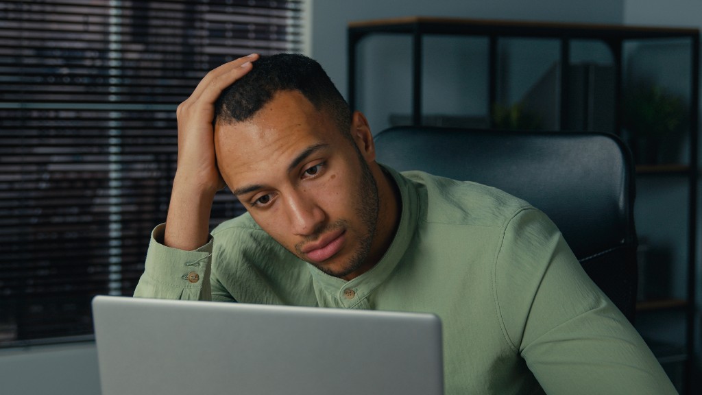 Rapaz jovem de camisa verde, mão na cabeça, sentado à mesa enquanto navega no notebook pesquisando o que a LGPD diz sobre vazamento de dados.