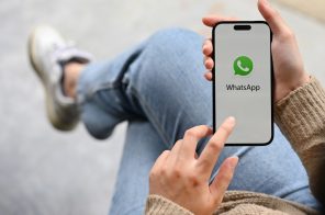 Mulher sentada com pernas cruzadas segurando celular para desligar a internet do WhatsApp.