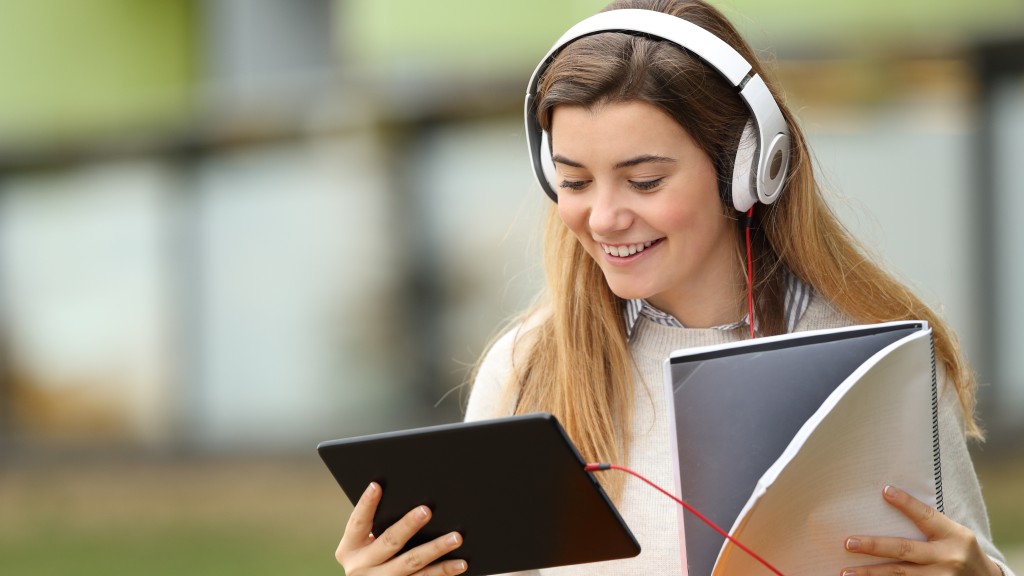 Jovem de blusa branca sorrindo, usando fones de ouvido brancos, segura um caderno e um tablet enquanto lê quadrinhos no app Desktop Comics.