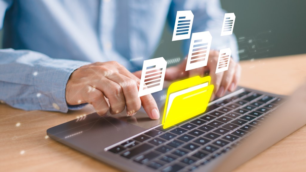 Pessoa mexendo no notebook e ícones flutuantes de pastas, representando o uso de backup dos arquivos para maior segurança na internet.