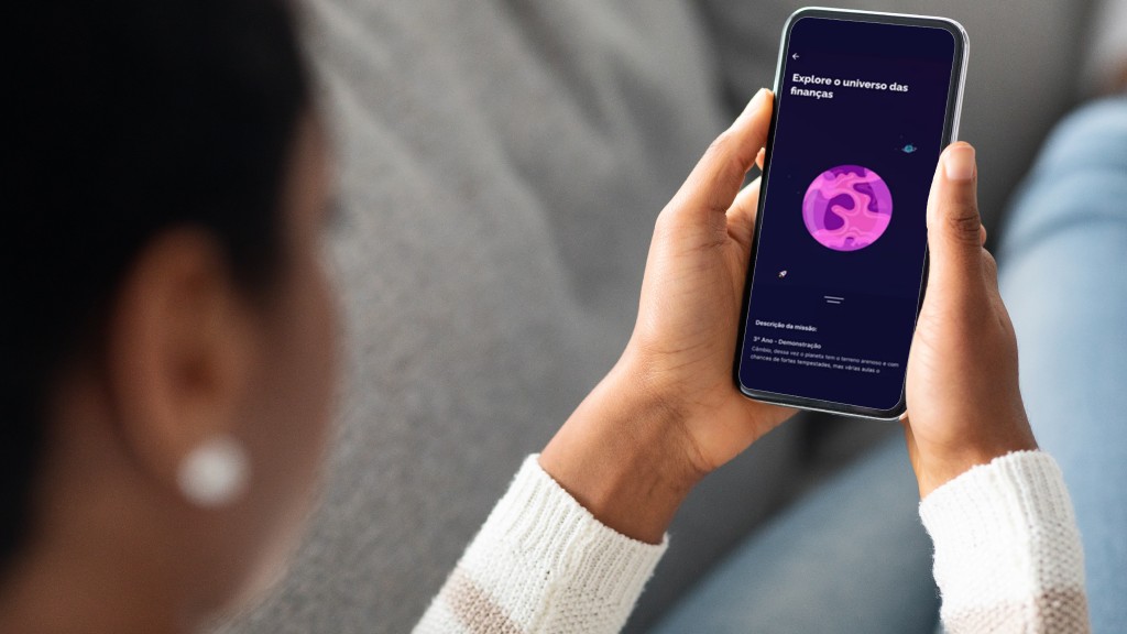 Mulher segurando celular com as duas mãos, com a tela exibindo o app Mooney, parceiro da Desktop Internet.