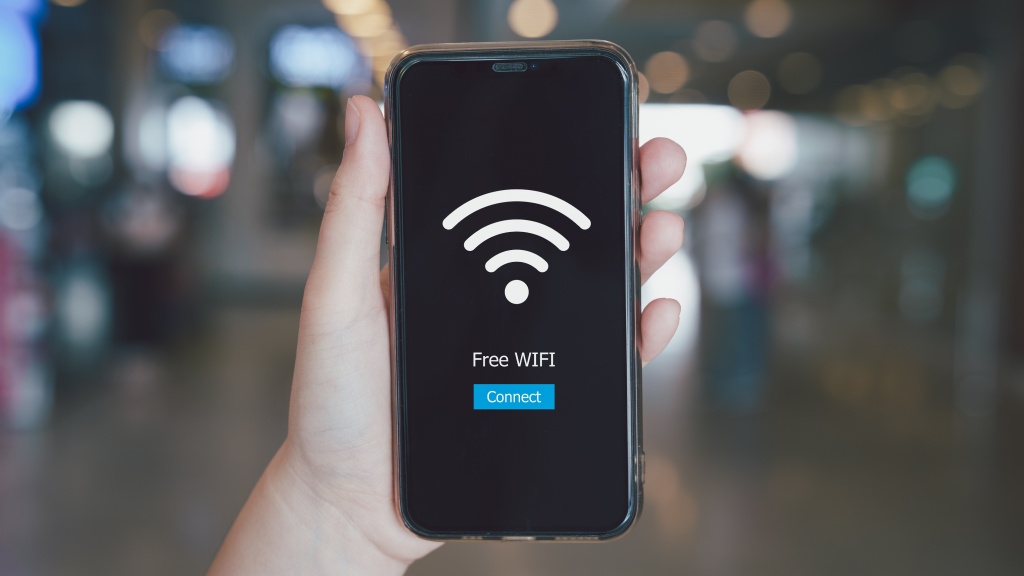 Mão segurando celular que exibe grande ícone de Wi-Fi branco, representando redes hotspot, com o texto "Free WiFi" e botão azul "Connect".
