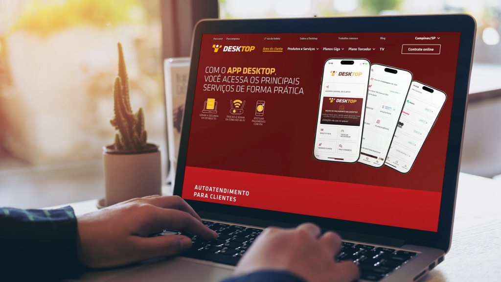 Acesse canais oficiais da empresa para evitar golpe do PIX Mãos digitando no notebook com a página da Área do Cliente Desktop aberta, simbolizando cuidados para evitar golpes no PIX.