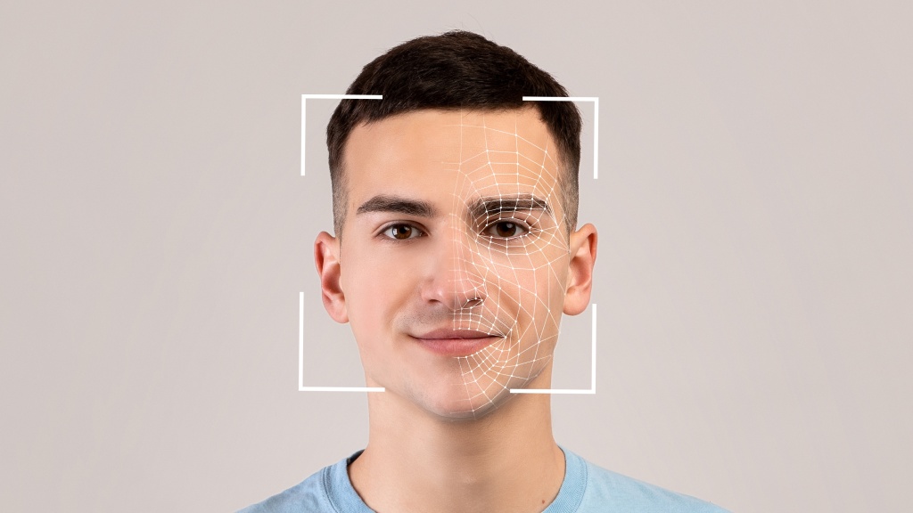 Homem olhando de frente para a lente da câmera, com enquadramento e mapeamento facial em seu rosco, representando riscos de conteúdos deepfake.