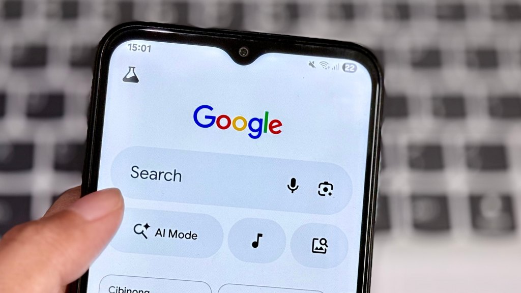 Mão segurando um celular que exibe a tela de pesquisa do Google, com o polegar próximo à barra de busca, representando dados salvos no histórico do navegador.