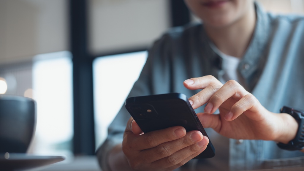Pessoa desfocada segurando o celular enquanto limpa o cache do aparelho, buscando melhorar o sinal.