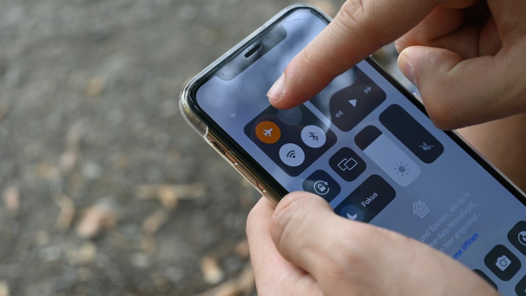 Mãos segurando um iPhone com a Central de Controle aberta, enquanto o dedo indicador aponta para o ícone do modo avião ativado.