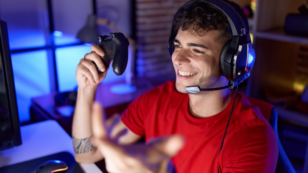 Rapaz gamer com camiseta vermelha, headphones pretos e controle de videogame na mão direita, sorrindo durante a partida após monitorar quantos Mega tem sua internet.