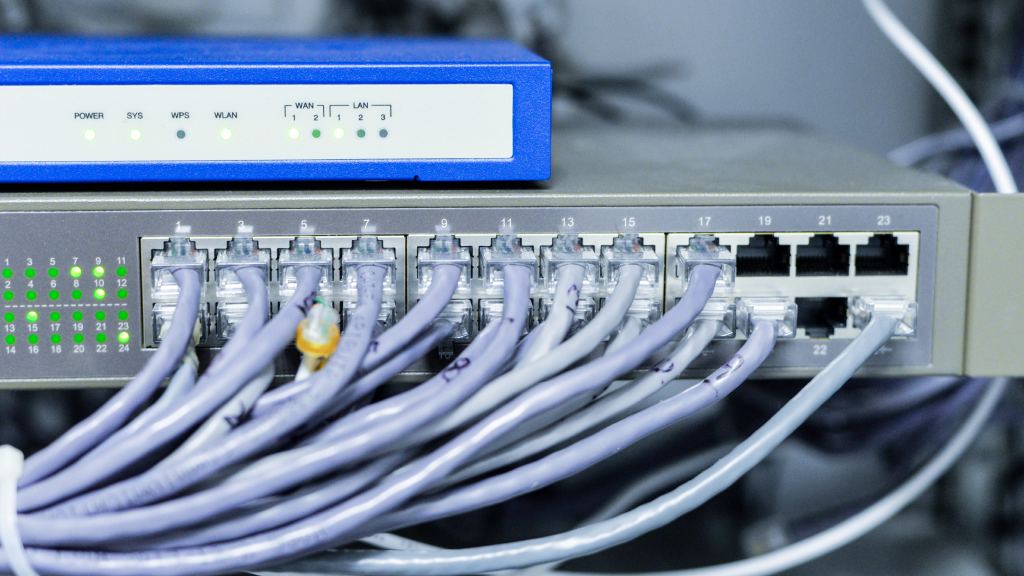 Equipamentos de rede com cabos conectados ilustram o que é um provedor de internet, mostrando a infraestrutura responsável por distribuir a conexão aos usuários.