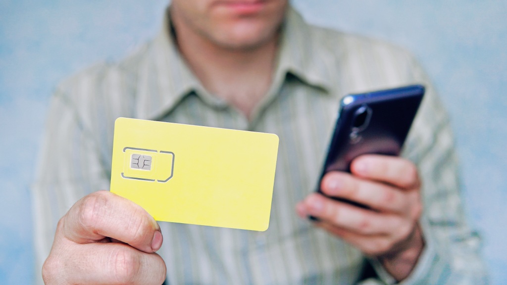 Homem desfocado segurando celular com uma mão e eSIM com a outra, simbolizando a portabilidade de chip.