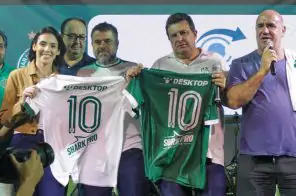 Imagem do evento do Guarani para apresentar a camisa do clube com o logo da Desktop. Na foto, cinco pessoa estão próximas, sendo que duas delas seguram a nova camisa de jogo do Guarani Futebol Clube. Ao lado direito da tela, a camisa na cor verde com o logo da Desktop no topo e o número 10 no centro, em branco. Ao lado esquerdo, a mesma versão da camisa, mas na cor branca e as informações em verde.
