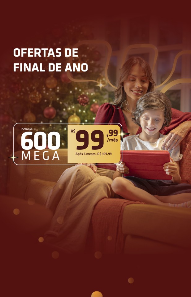 Banner de final de ano da Desktop com mãe e filho sentados no sofá ao lado de uma árvore de Natal, esfumaçado em vermelho, acompanhado do texto “Ofertas de final de ano” e de um card com a oferta “Planos de 600 Mega – R$ 99,99/mês | Após 6 meses, R$ 109,99”.