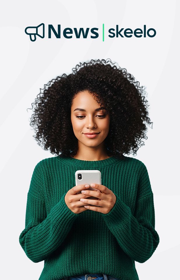 Banner do Skeelo News, app parceiro da Desktop, exibindo uma mulher com blusa verde navegando no celular, com o logo “Skeelo News” no topo, sobre fundo em cor cinza.
